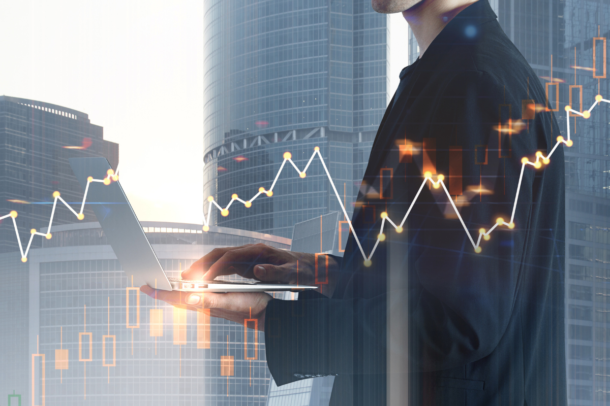 A person typing on a laptop overlaid by a graph going steadily upwards overlaid on an office skyscraper.