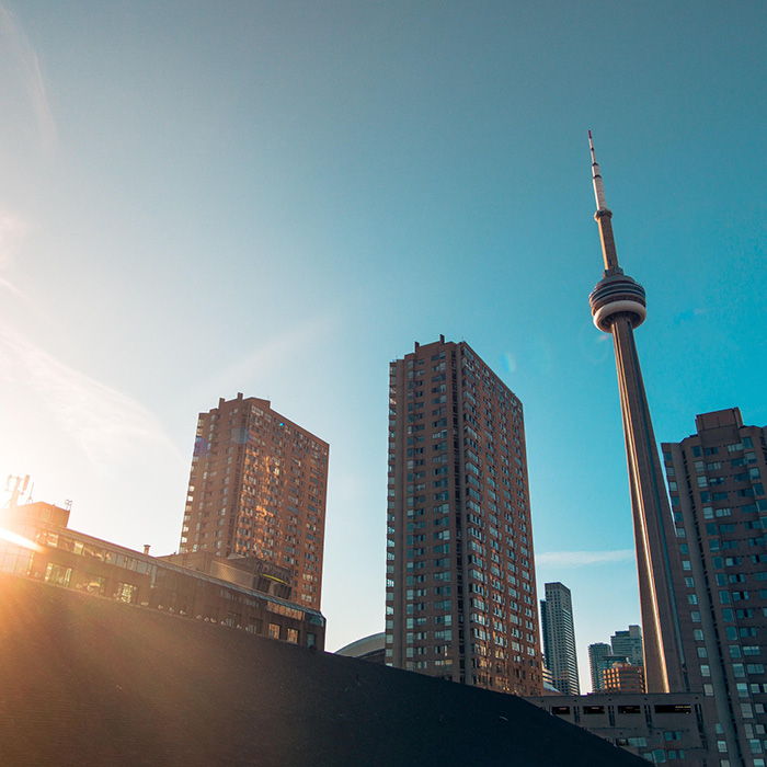 The CN Tower beside two towers during sunset. 