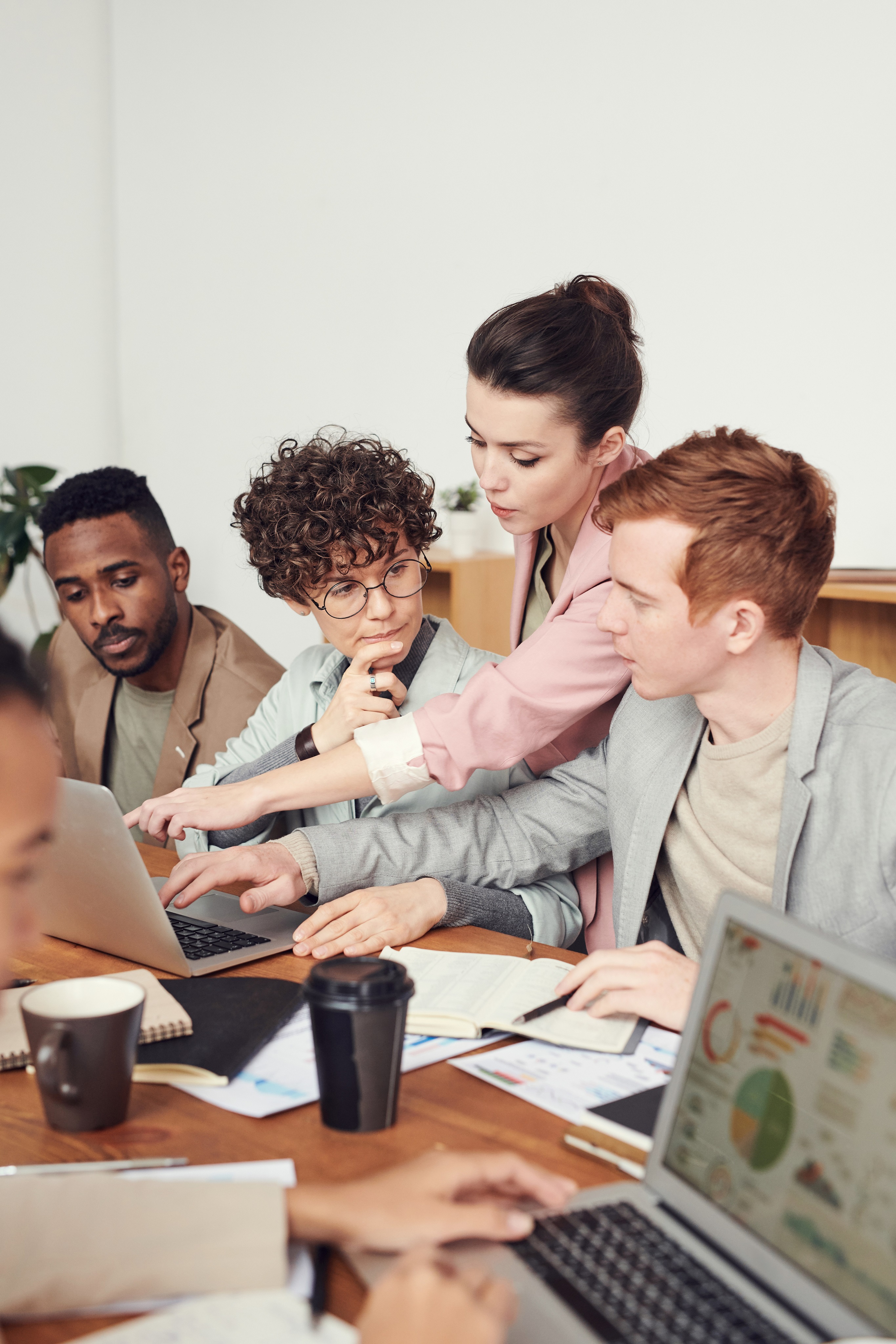 A woman helps a man with something on their workscreen in a meeting.