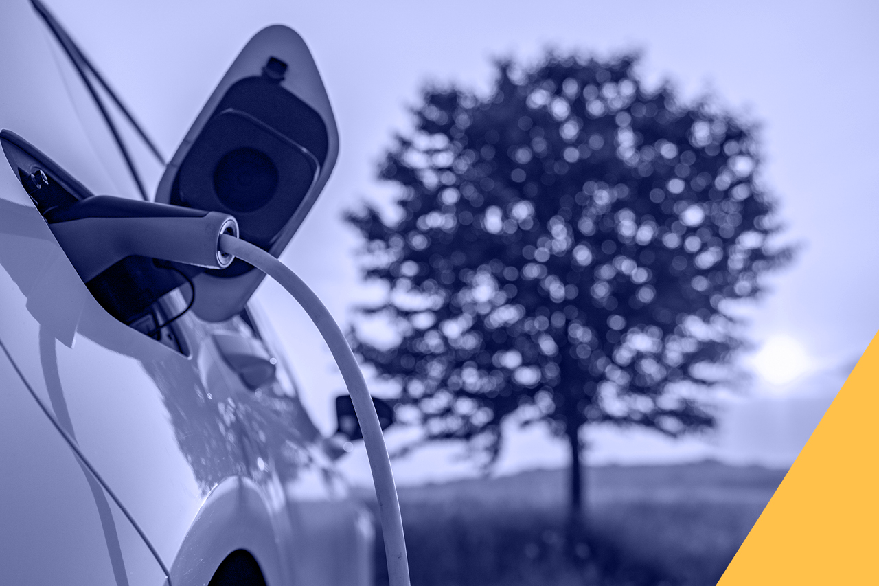 An EV vehicle being charged with a tree in full bloom in the background.