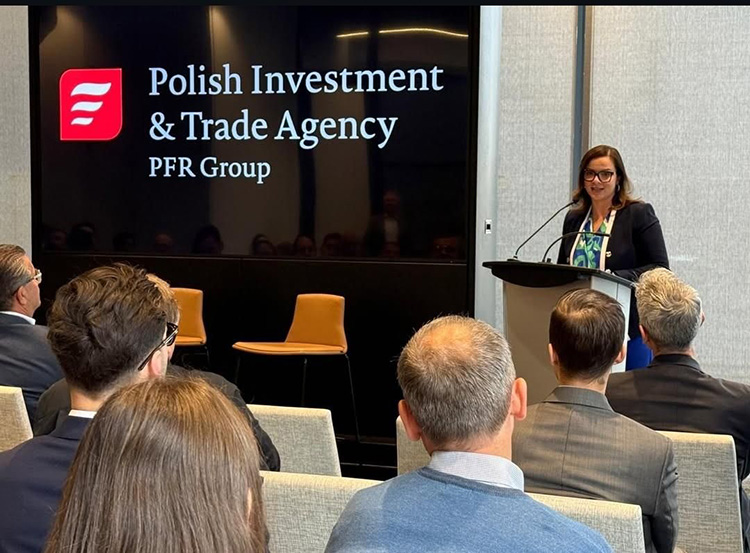A presenter speaks in front of a screen that reads Polish Investment and Trade Agency - PFR Group