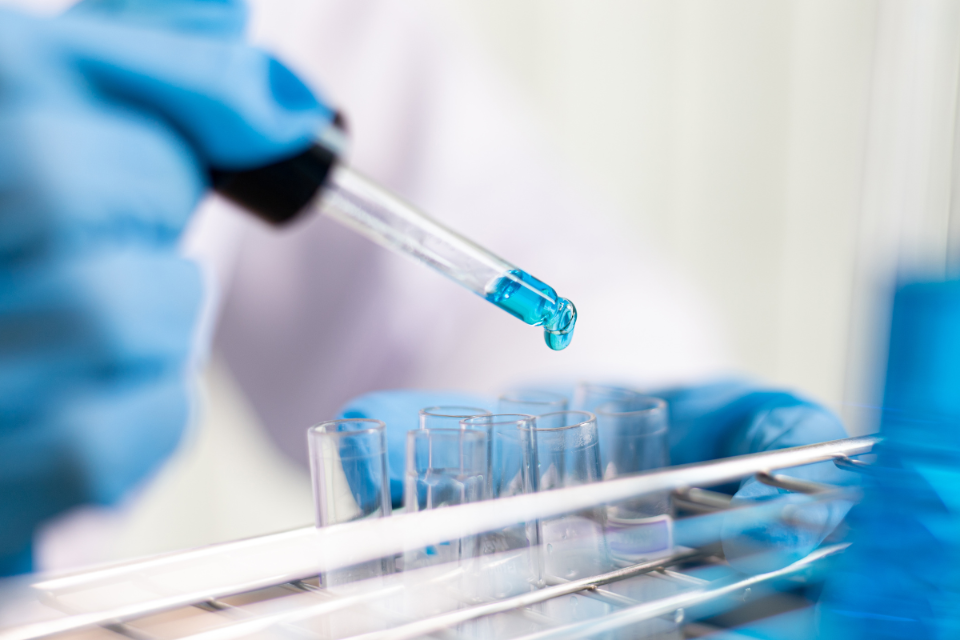 A person putting a solution into a test tube.