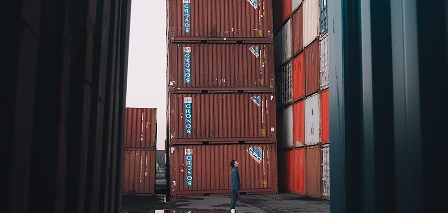A person stands in the middle of a small mountain of shipping containers.
