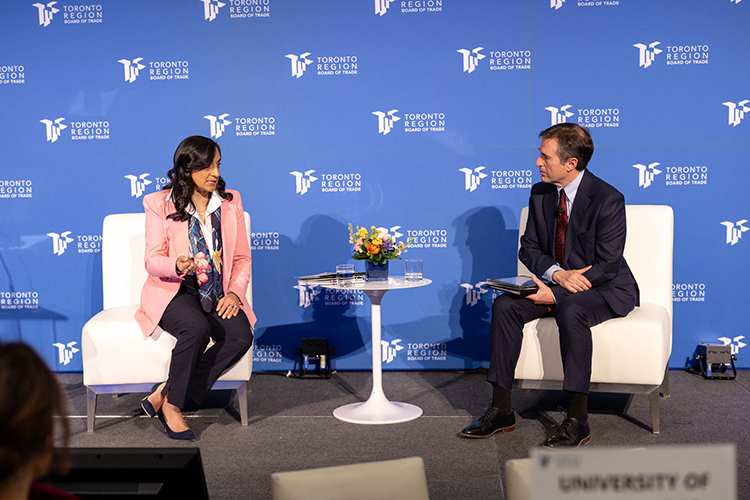 Two seated people have a discussion on stage