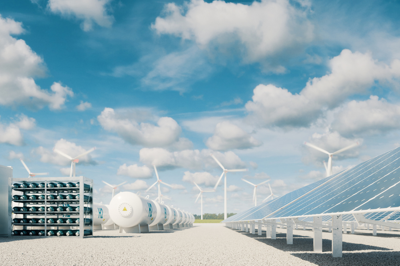 A blue sky with pipelines and propane tanks on either side of a gravel road.