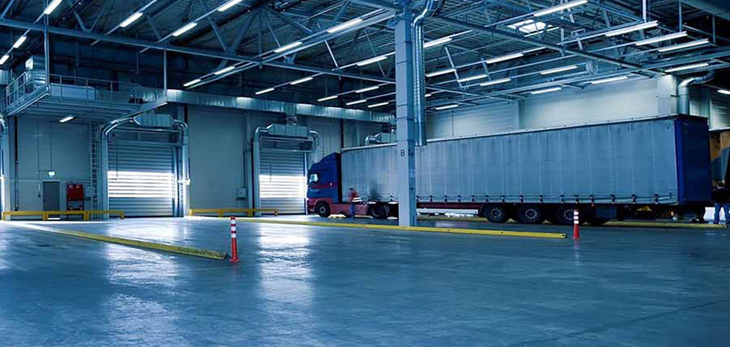 A large, mostly empty warehouse containing a single transportation truck.
