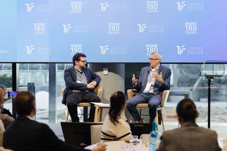 Two men seated speaking on a stage