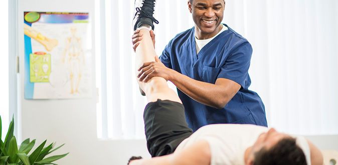 Physiotherapist helping patient with stretches on the table.