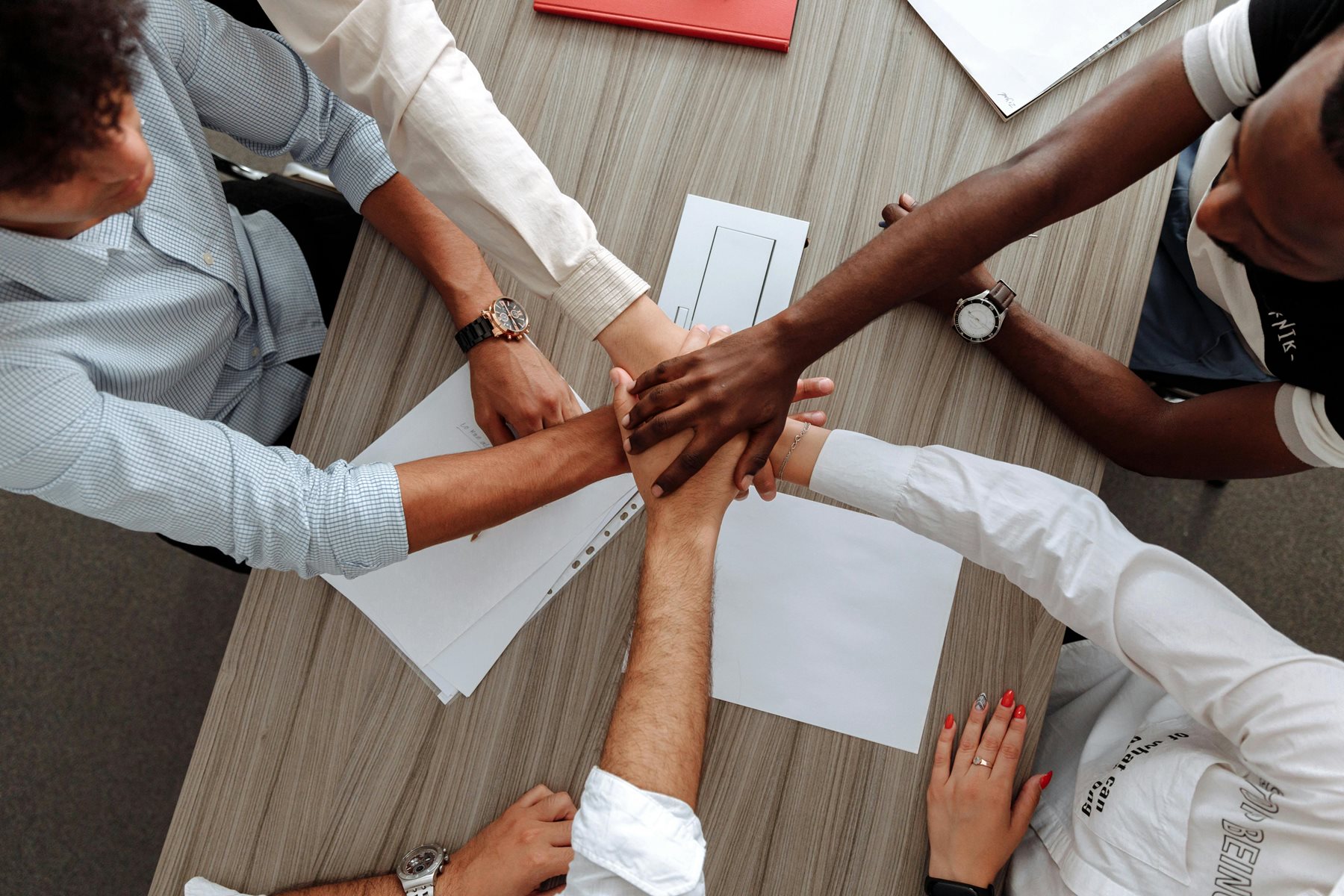 A group of young people putting their hands together, unified.