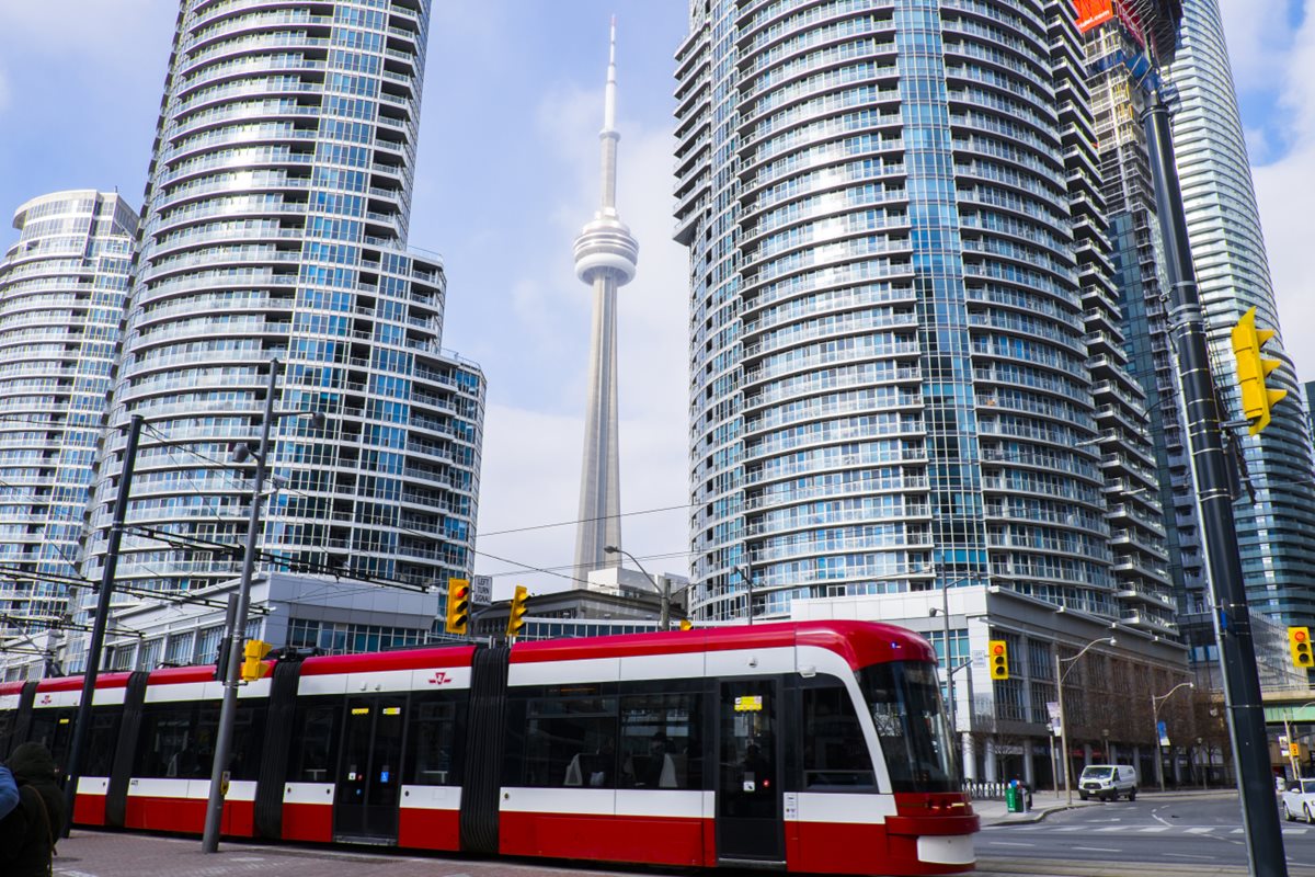 A TTC Streetcar makes it way through Downtown Toronto while the CN Tower looms behind.