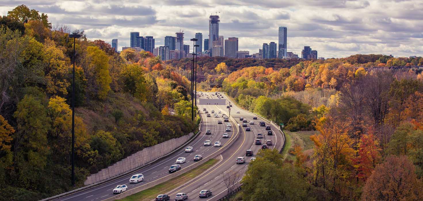Active highway with autumn foliage. A view of the city skyline can be in the distance.