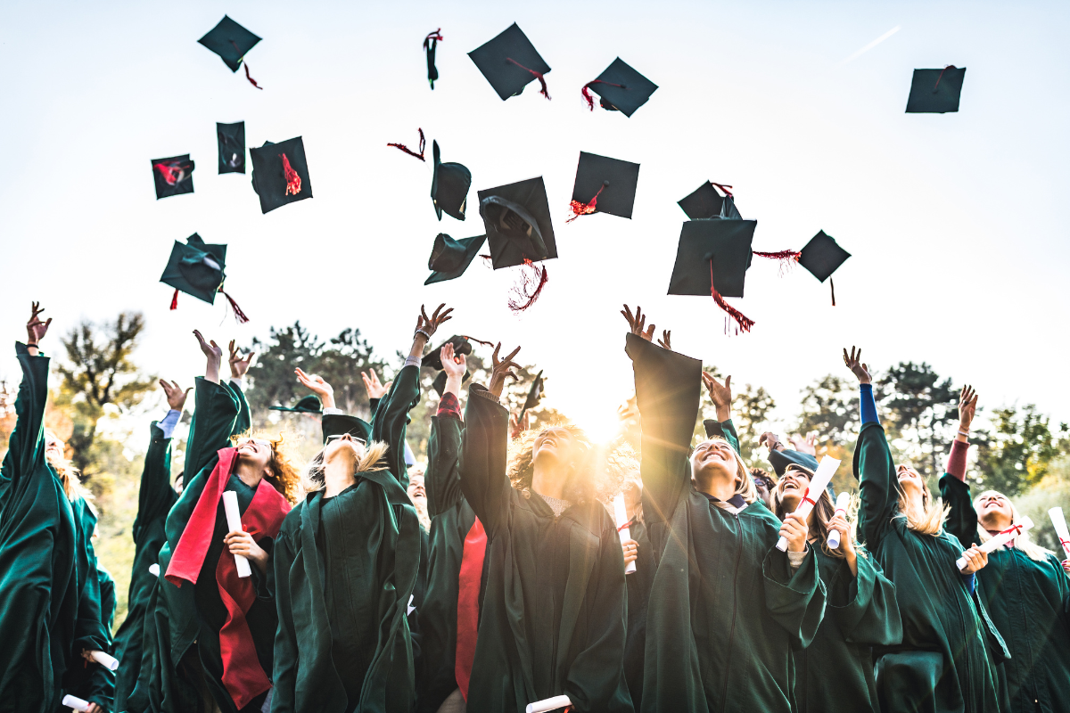 A group of graduating students tossing their motarboards in the air, as is tradition.