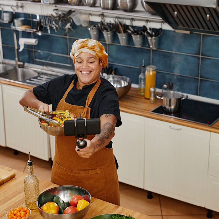 Woman filming herself in kitchen setting