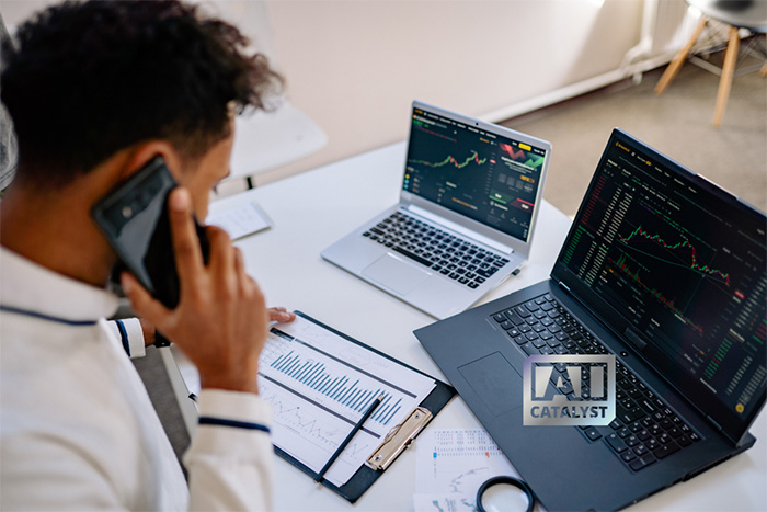 A man reviews stock charts on a laptop while on the phone