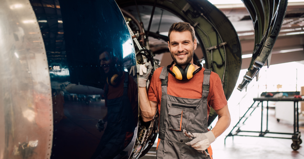 An airplane technician smiling confidently while on the job.
