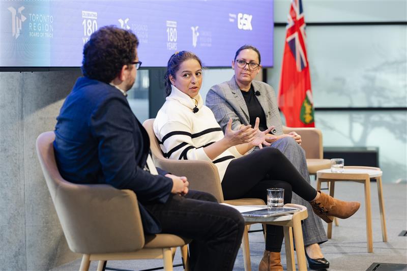 Three people seated on a stage, speaking