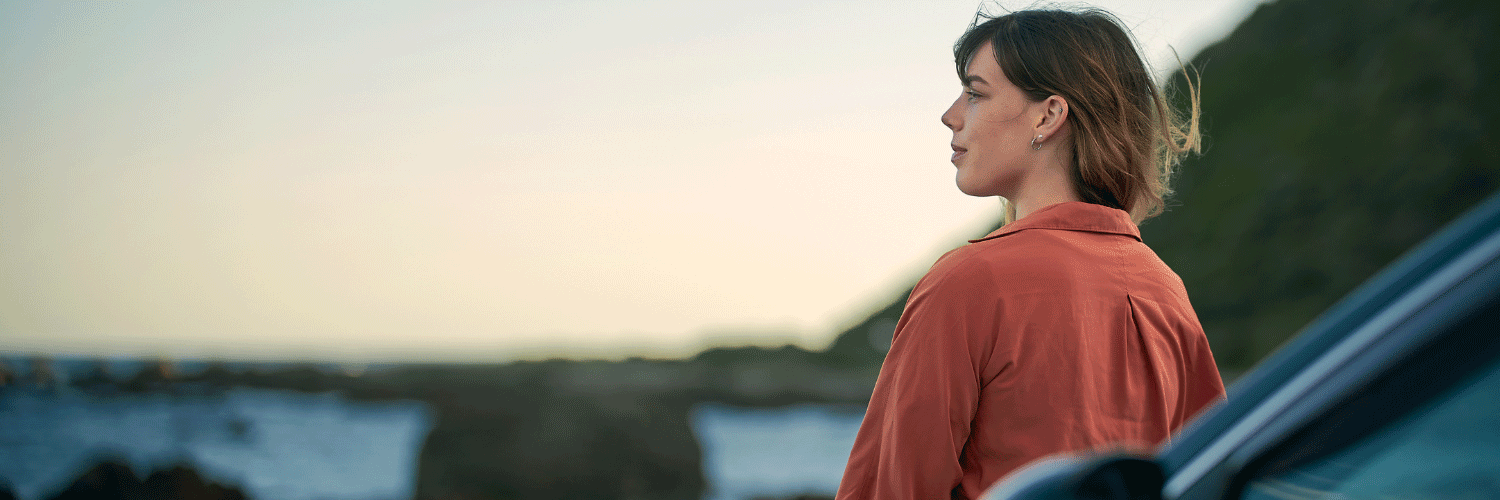 Woman leaning on her car looking at nature