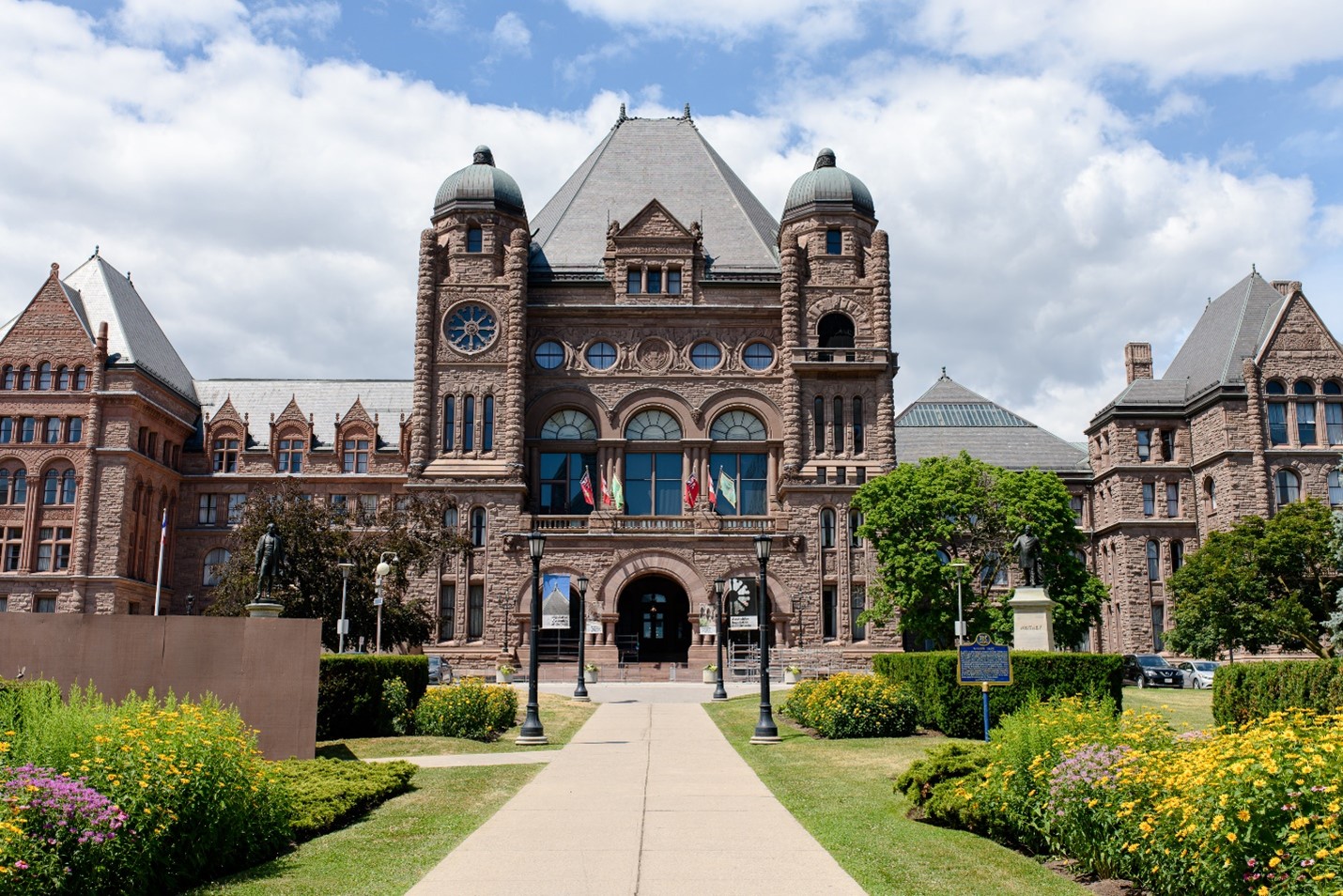 Queen's Park in Toronto, on a background of blue sky and clouds.