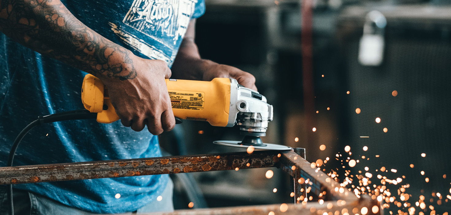 A manufacturing worker grinding a steel frame.