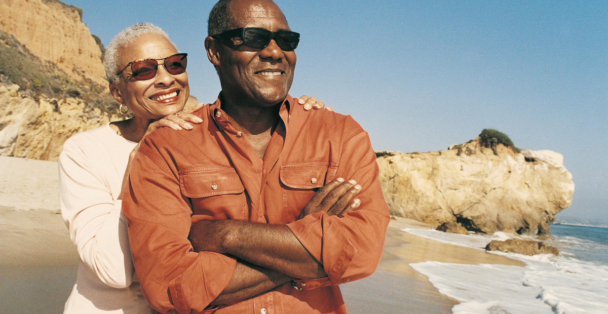 An elderly couple at the beach, looking happy and relaxed.