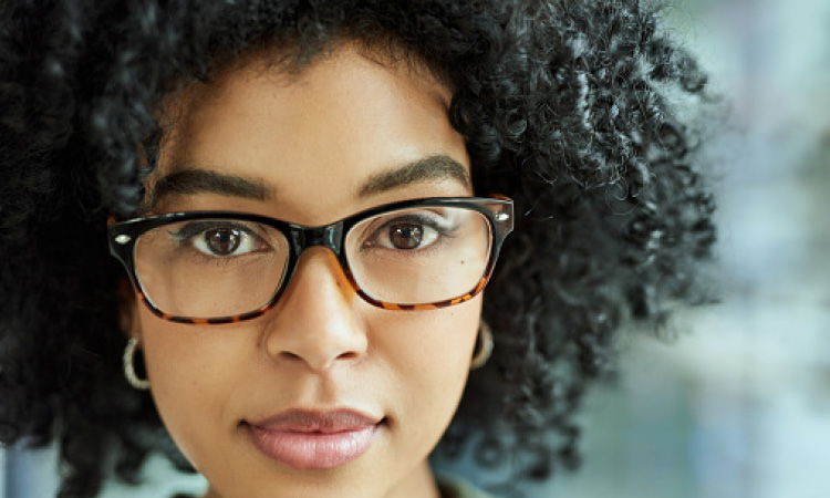 Woman with glasses, slightly smiling and looking forward.