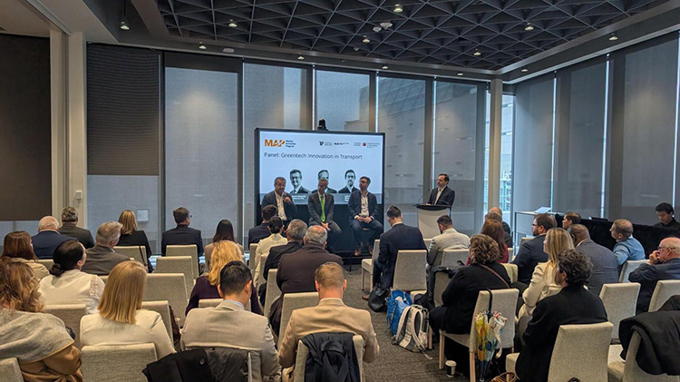Attendees watch Panel participants in a large conference space