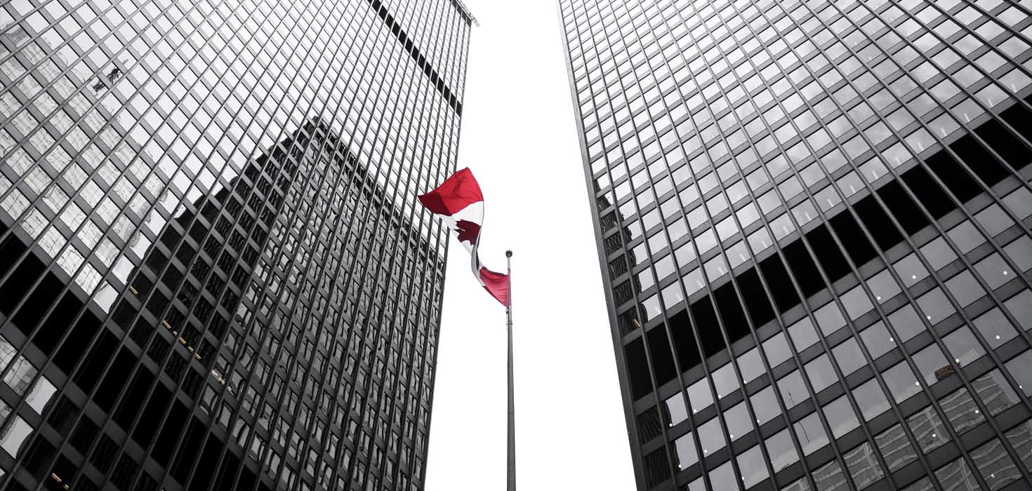 Canadian flag flies between two sky scrapers