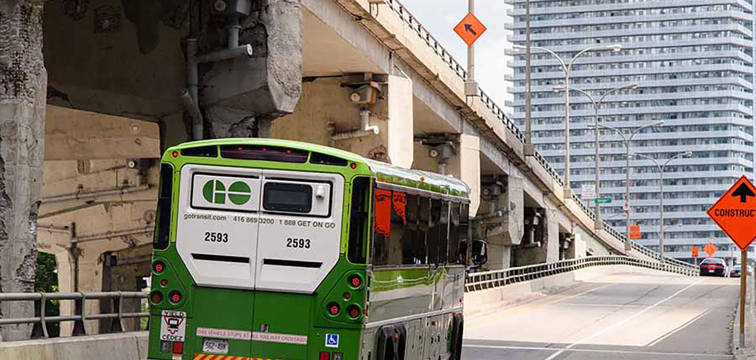 A GO Bus ascends an entrance ramp to an elevated highway.
